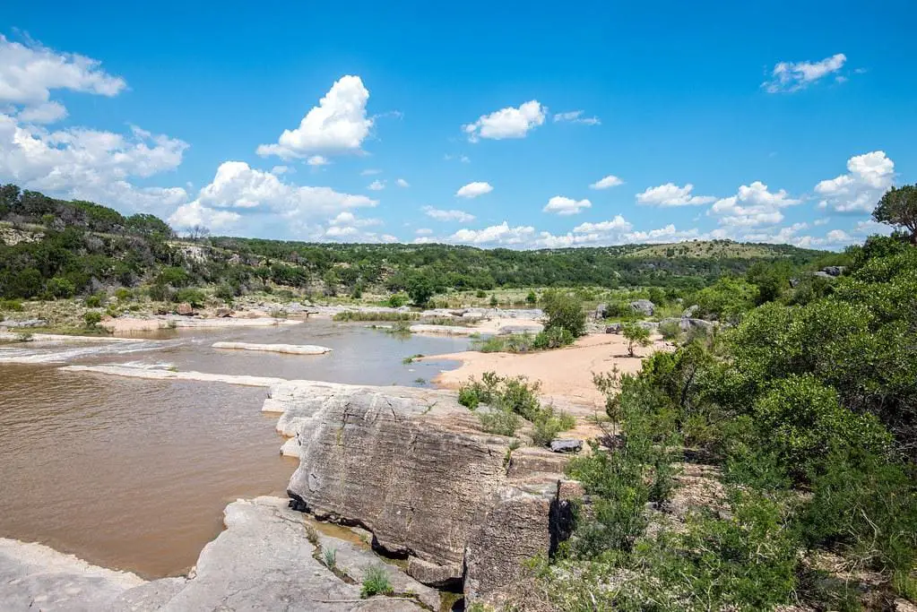 Scenic view of Pedernales Falls cascading over limestone formations with the Texas Hill Country in the background